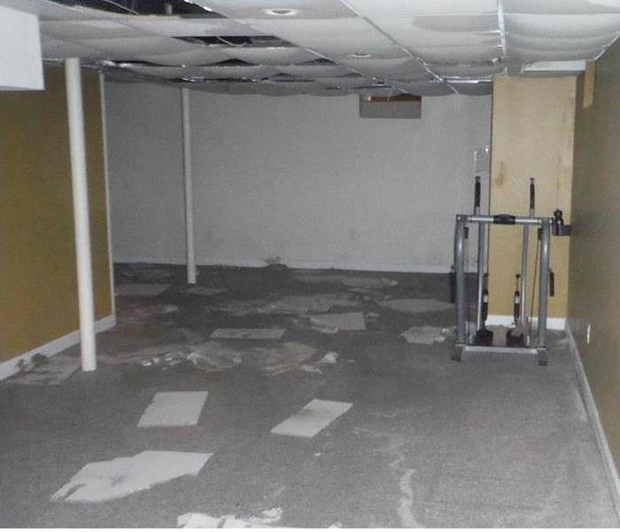 water damaged ceiling tiles, flooded commercial-grade floor, and an exercise machine