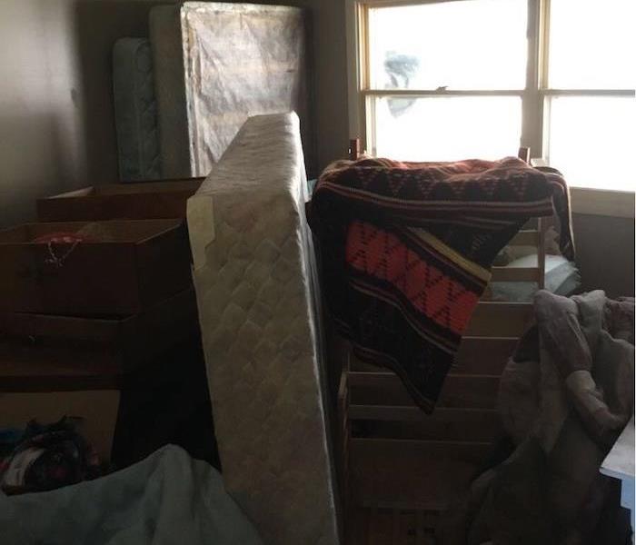 Room with stacked up boxes, mattresses and debris