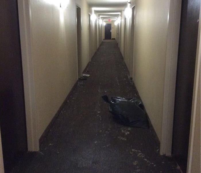 Office hallway with a trash bag and debris on the floor