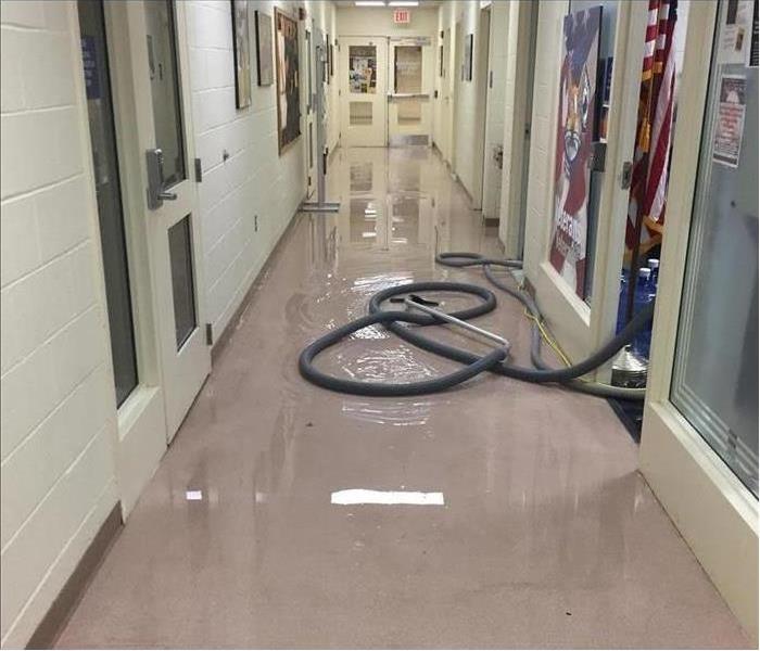 water pooling on floor of hallway, visible vacuum hoses for removal