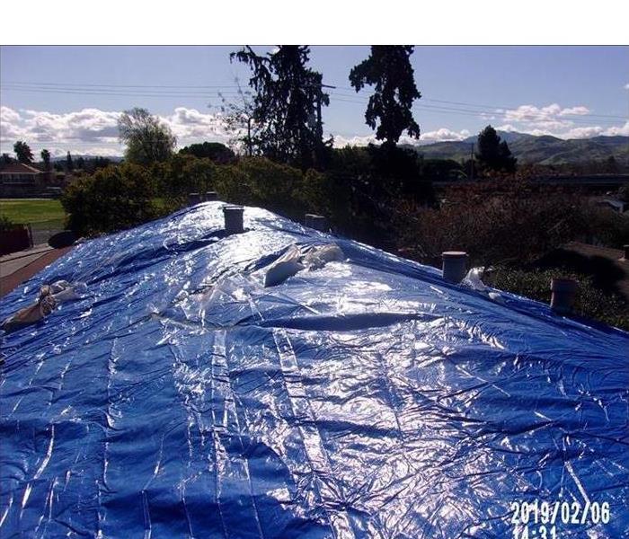 long view of a roof covered with a blue tarp