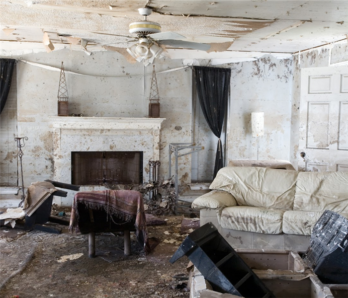 a storm damaged living room with debris and ruined furniture everywhere
