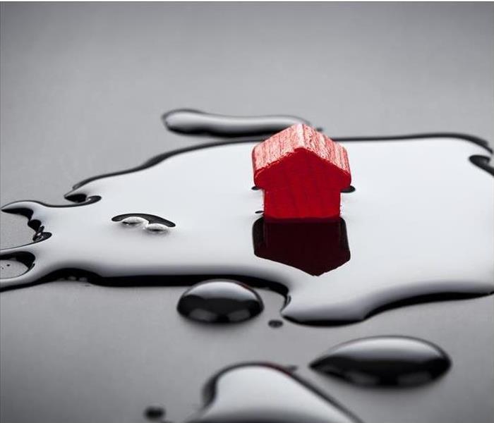 small, red toy house sitting in puddle of water