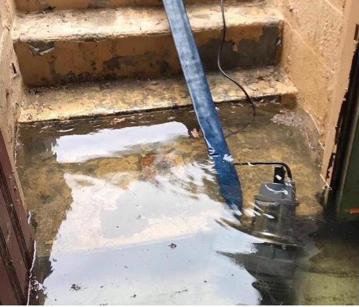 submersible pump, blue hose, flooded basement entrance area by the steps